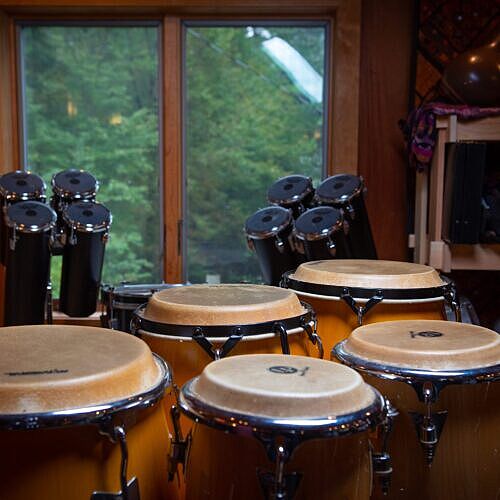 a set of five congas and a complete set of 8 octobans in front of a window